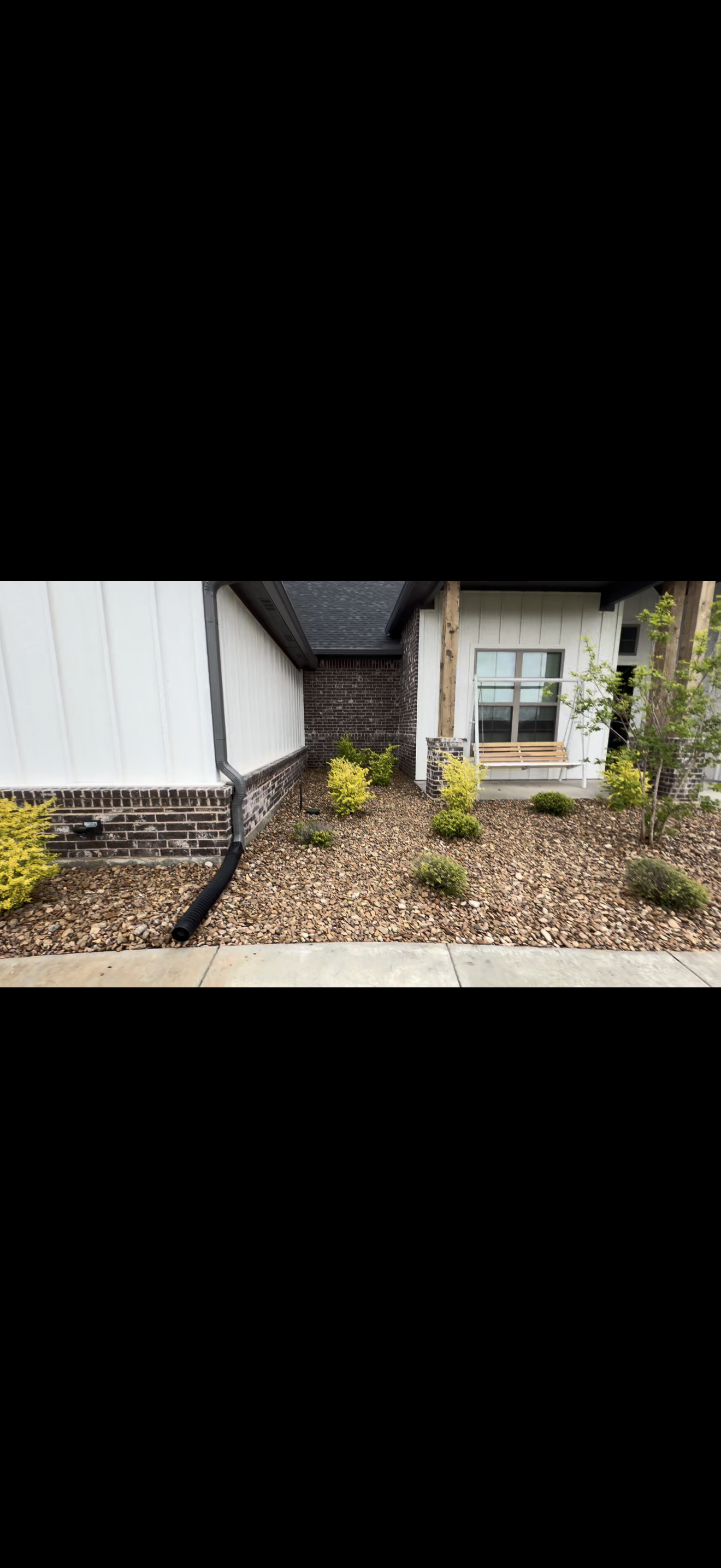 Gravel landscape bed with shrubs along modern home exterior