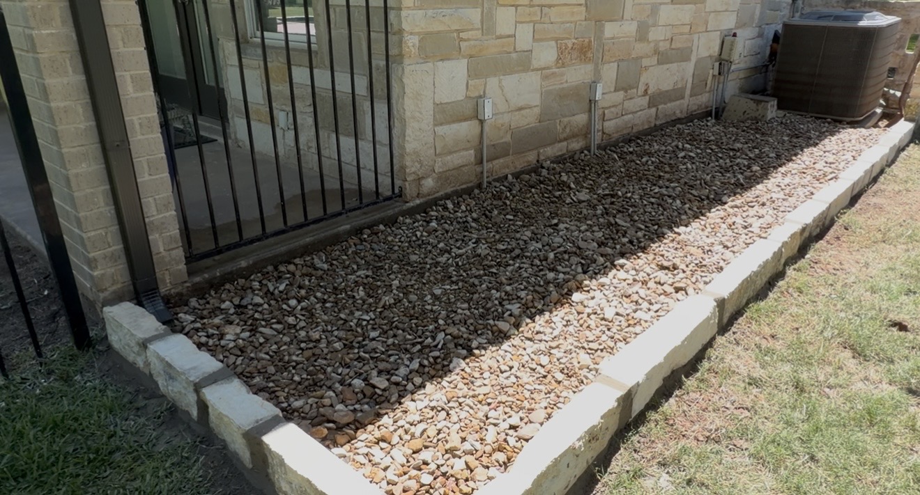 Rock and gravel bed with stone border along home exterior