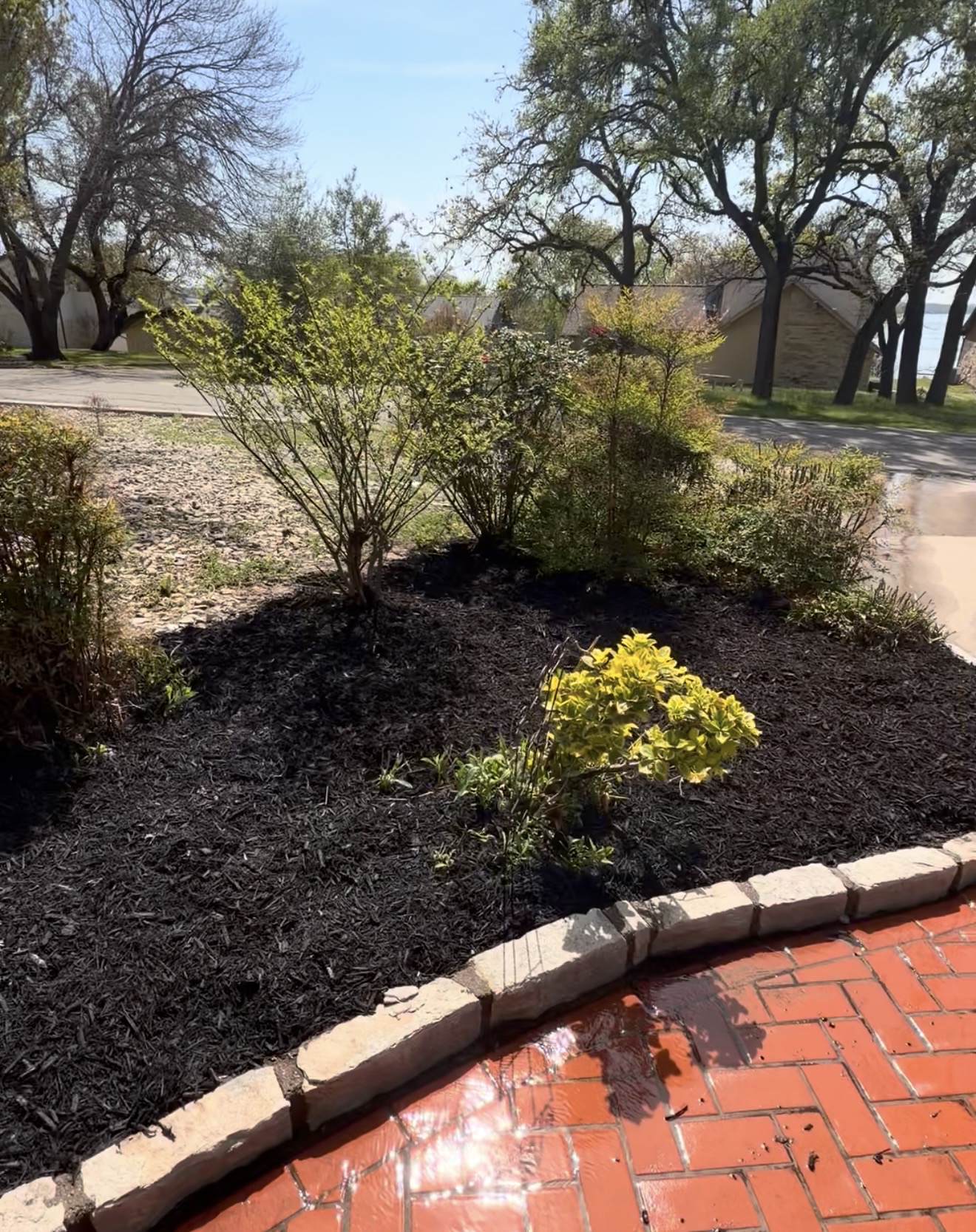 Mulch planting bed with shrubs and brick border by Muro's Landscape